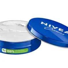 Nivea Creme w otwartym, niebieskim, metalowym opakowaniu z białym kremem.